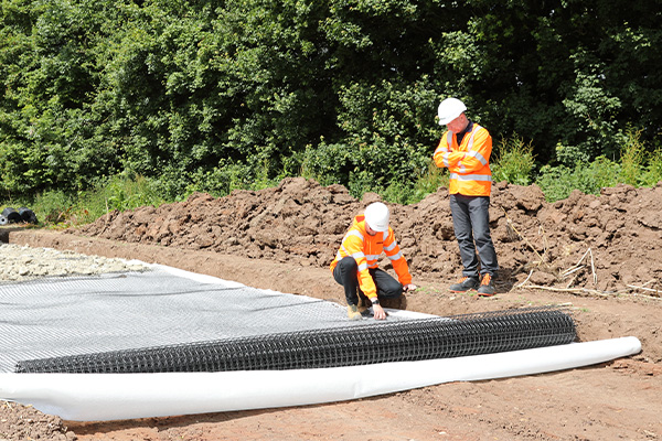 Two workers assessing a roll of geogrid