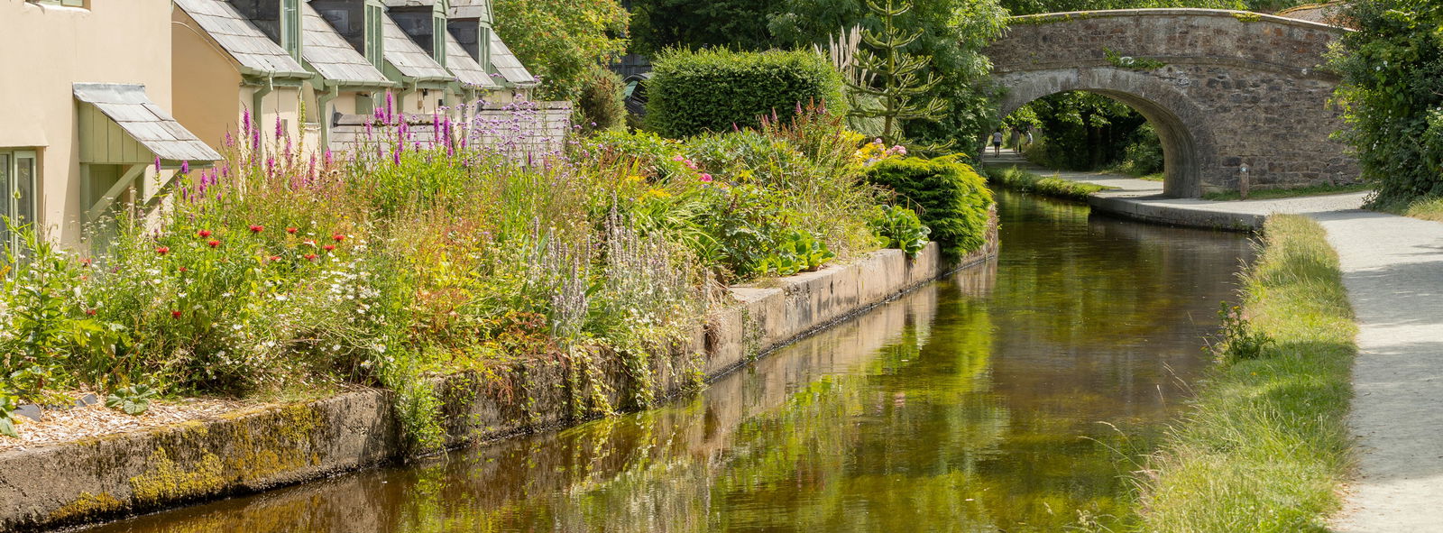 Cottages along side a canal with a bridge in the distance