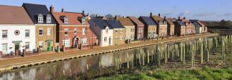 Newly planted treeline alongside a canal and new build housing development
